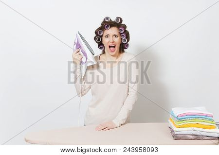 Crazy Fun Housewife With Curlers On Hair In Light Clothes Ironing Family Clothing On Ironing Board W