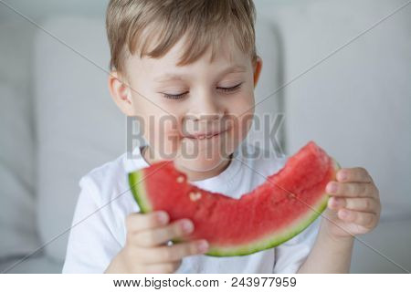 A Small Cute Boy 4 Years Old Is Eating A Watermelon. Summer. Heat. Watermelon. Portrait Of A Happy B