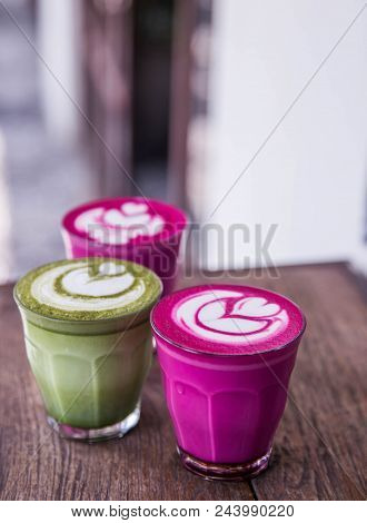 Three Colorful Beetroot, Matcha Lattes On The Wooden Background Closed To White Wall. Trendy Healthy