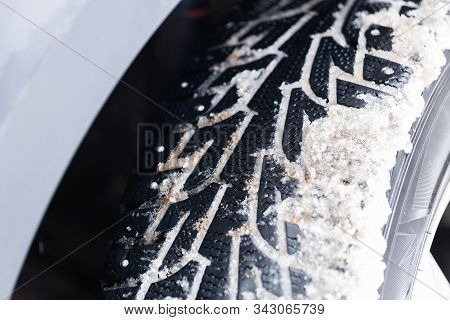An Unadorned Picture Of Winter Car Wheel With Metal Spikes On Snow Close-up