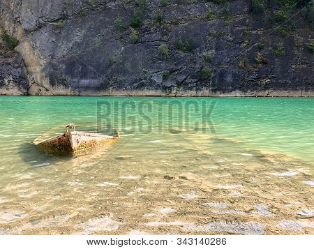 Abandoned Boat In Flooded Quarry With Blue Crystal Water. Diver Site With Fresh Blue And Clean Water