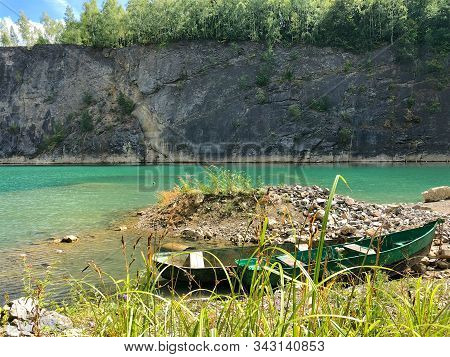 Abandoned Boat In Flooded Quarry With Blue Crystal Water. Diver Site With Fresh Blue And Clean Water