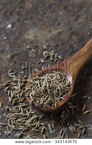 Cumin Seeds In Wooden Spoon On A Textured Background