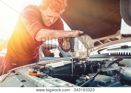 The Concept Of Disability Of People And Their Adaptation To Life. A Blond Disabled Man Repairs A Car