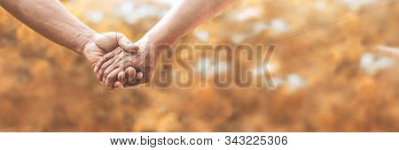 Senior Couple Holding Hands Together Over Nature Background.