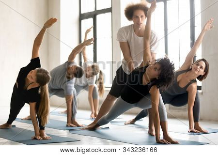 Instructor Helping Woman With Utthita Parsvakonasana Exercise, Practicing Yoga