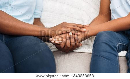 Close Up Black Woman And Child Sitting On Couch Holding Hands, Saying Sorry, Apologize