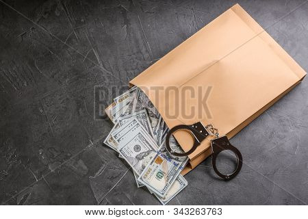 Envelope With Dollar Bills And Handcuffs On Grey Stone Table, Top View. Bribe Concept