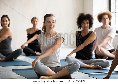 Young Diverse People Practicing Yoga, Sitting In Parivritta Sukhasana Pose