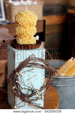 Tall Wooden Stand With Pretty Carved Candle On Top And Long Tapered Ones In Metal Can Beside It On T