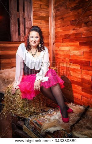 Portrait Of Fat Plump Fun Charming Cute Woman With Black Curly Hair In The Room With Hay And Straw