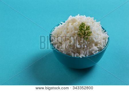 Cooked Plain White Basmati Rice With Corriander In A Blue Bowl On Blue Background