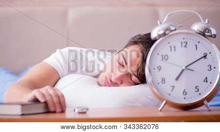 Man in bed frustrated suffering from insomnia with an alarm cloc