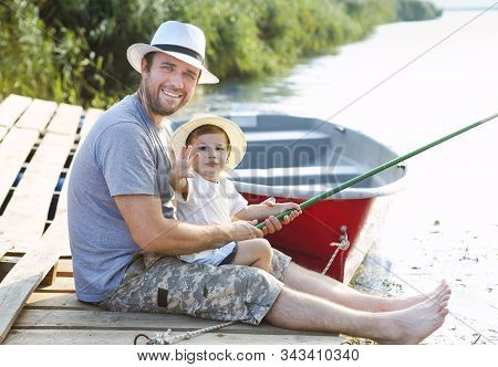 Father With Little Baby Son Fishing On The Shore Of The River. Hobby Concept. Angling, Fishing, Acti