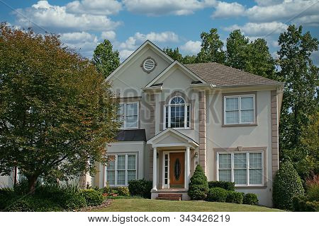 Nice Stucco House With Greren Lawn Against Blue Sky