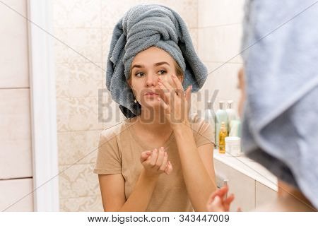 A Beautiful Girl With A Towel On Her Head Sticks Hydrogel Patches Under Her Eyes On Her Face. The Gi