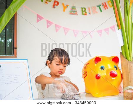 The Little Girl Hand Try To Putting Coin In The Golden Piggy Bank Received At A Birthday Party.