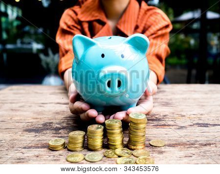 Business Woman Hand Carry Blue Piggy Bank With Gold Coins Pile Growth Graph, Saving Money For Future