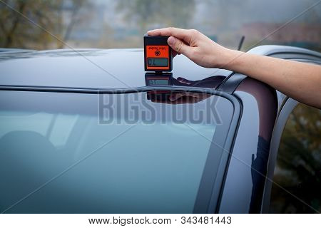 Measuring The Thickness Of The Car Paint Coating In Black Color Using A Paint Thickness Gauge.