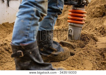 A Close Up And Selective Focus Shot On The Legs Of A Man Using A Heavy Earth Compactor On A Construc
