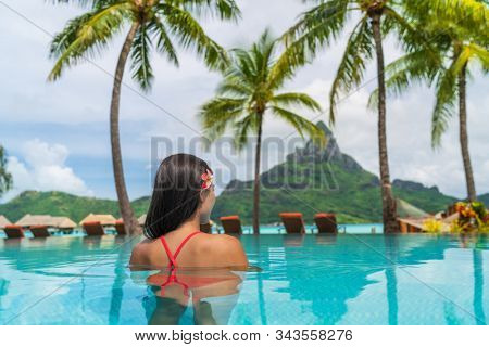 Hotel resort vacation tourist swimming in hotel pool enjoying view of famous French Polynesia honeymoon travel destination icon - Otemanu peak mount in Bora Bora island, Tahiti luxury stay getaway.