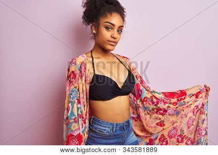 Young beautiful african american woman on vacation standing wearing bikini and colorful caftan