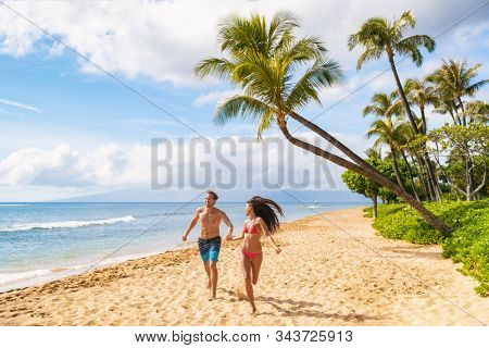 Happy Hawaii beach fun young people running enjoying summer vacations in Maui, Kaanapali beach, USA travel lifestyle.