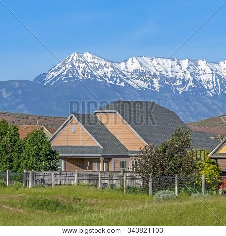 Square Single Storey Houses Against Striking Snow Capped Mountain And Vibrant Blue Sky