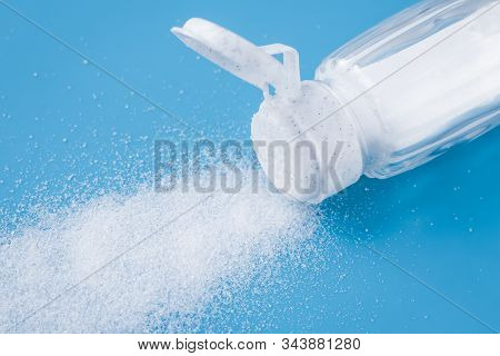 The Salt Shaker On Blue Background. Sprinkled Crystallised Salt. The Glass Bottle With Sodium Chlori