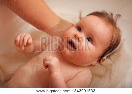 Cute Newborn Baby Bathes In The Bathroom. The Concept Of A Toddlers  Swimming
