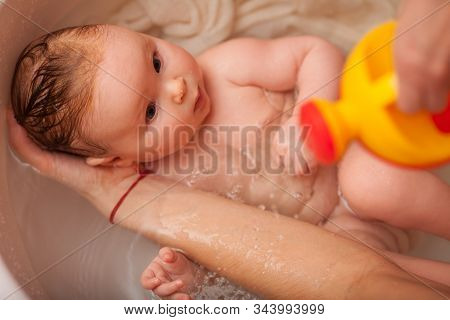 Cute Newborn Baby Bathes In The Bathroom. The Concept Of A Toddlers  Swimming