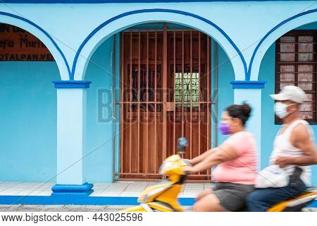 Tlacotalpan, Veracruz, Mexico- August 20, 2021: Couple Of Locals Driving A Motorcycle, Passing A Typ
