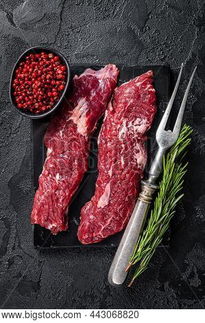 Raw Machete Steak Or Hanging Tender Cut With Herbs. Black Background. Top View