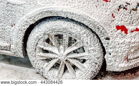 Front Right Wheel Of A Red Car On Which Foam Is Applied To Wash A Car At A Self-service Car Wash