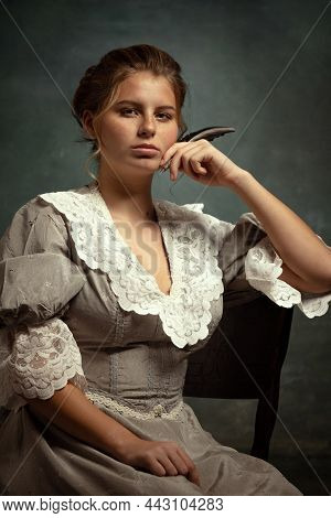Close-up Portrait Of Young Beautiful Girl In Gray Dress Of Medieval Style Isolated On Dark Backgroun