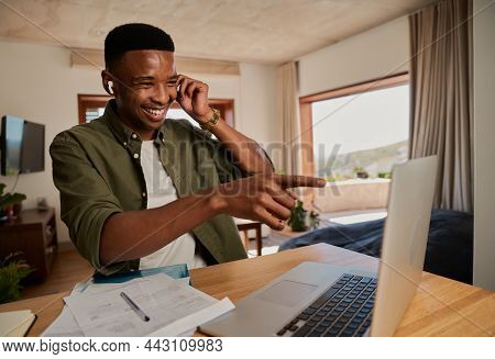 Young Adult Black Male Wearing Earphones Having A Good Time With Colleagues While On Online Meeting.