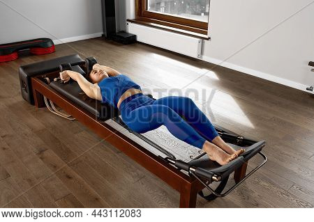 The Instructor Does Exercises On The Reformer, A Beautiful Girl Trains On The Modern Reformer Simula