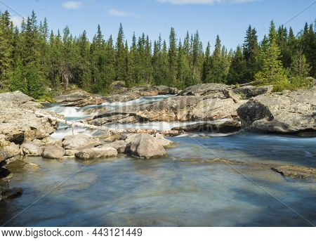 Beautiful Landscape With Long Exposure Water Stream And Cascade Of River Kamajokk, Boulders And Spru