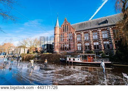 People Ice Scating On Frozen Canal In City Center In Netherlands. Peoples Making Pictures, Walking A
