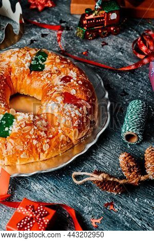 closeup of a spanish roscon de reyes, the typical three kings cake eaten traditionally on epiphany day, on a gray rustic table, full of gifts and ornaments