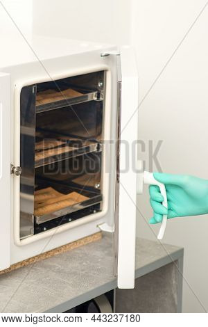 Beautician In Protective Gloves Close The Door Of The Machine For Disinfection Of Tools Before The D