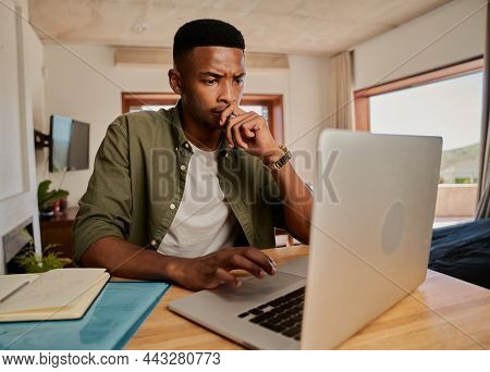 Young Adult Black Male Worrying While Typing On His Laptop. Sitting In Modern Apartment Working From