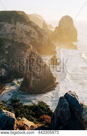 Top view from Miradouro da Praia do Caneiro, cliffs and surf in the Atlantic Ocean in Portugal.