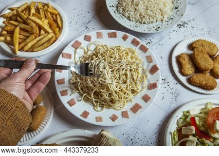 Close Up Of A Man's Hand With A Fork Taking Spaguettis From The Restaurant Table