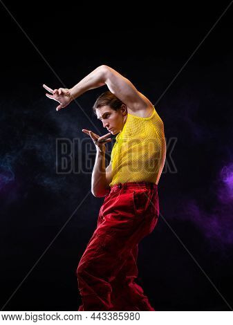 A Young Muscular Man In A Bright Outfit Poses In A Pretentious Pose, Style And Grotesque. An Attract