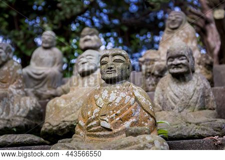 Figures Of Japanese Buddhist Monks In Close-up. Stone Statues Of Seated Monks