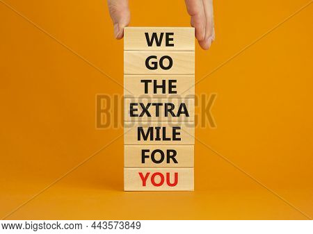 Go The Extra Mile Symbol. Wooden Blocks With Words 'we Go The Extra Mile For You'. Businessman Hand.