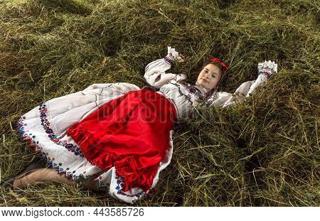 Salaj, Romania - May 15, 2018: Young Rural Girl Wearing Traditional Costumes Sitting In A Hayloft At