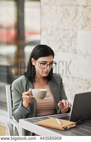 Vertical Portrait Of Young Successful Businesswoman Iusing Laptop At Outdoor Cafe