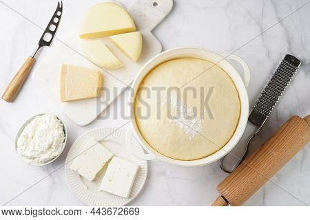 Various Cheese Types On Marble And Porcelain Plates And Fresh Dough - Ingredients For Traditional Ge